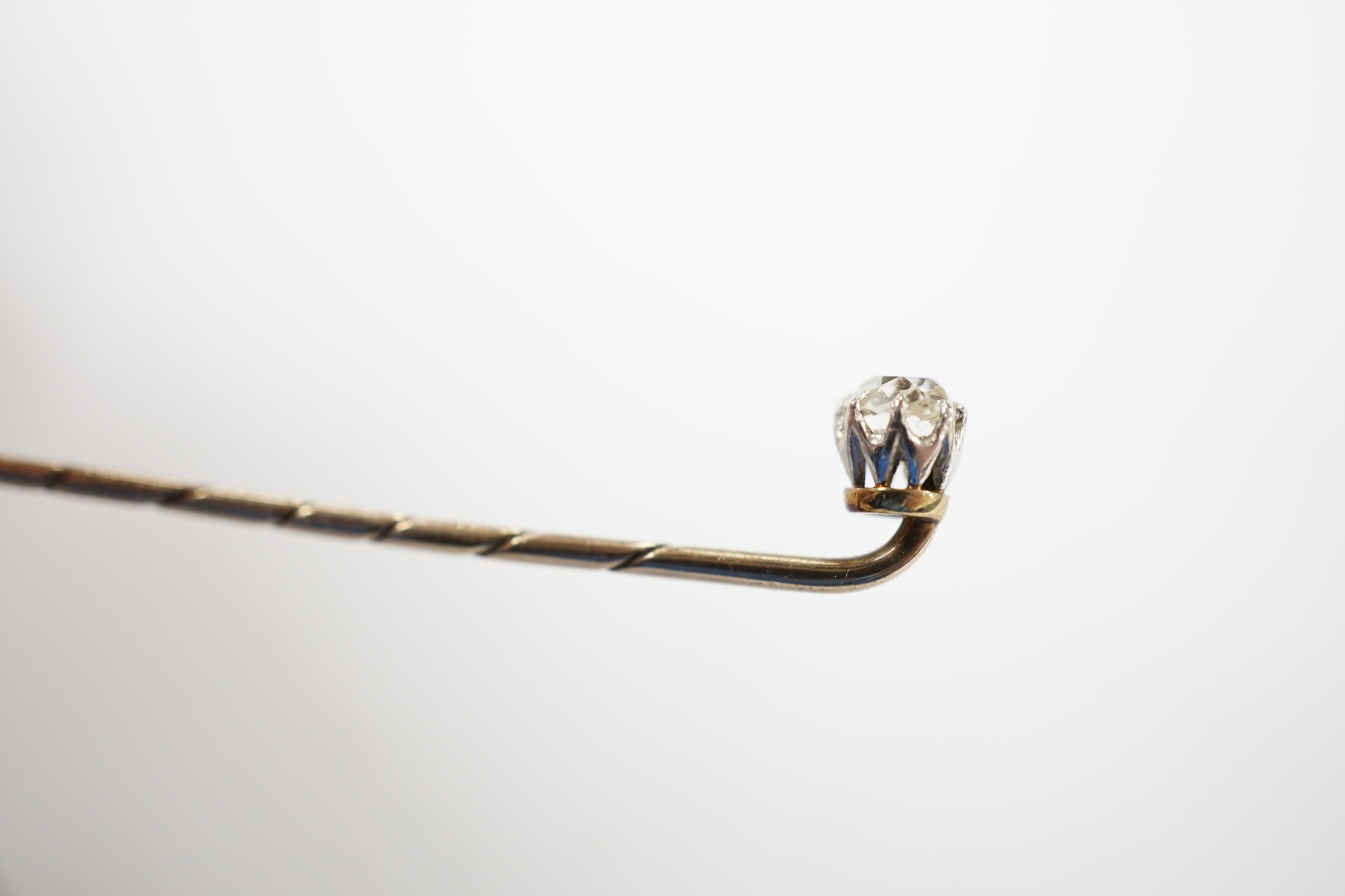 An early 20th century cased yellow metal and cushion cut solitaire diamond set stick pin, 57mm, gross weight 1.3 grams.